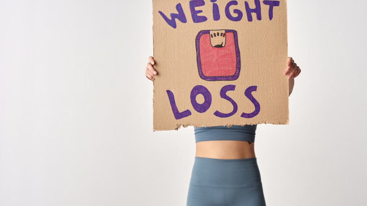 Person holding 'weight loss' sign for fitness motivation and health goals.